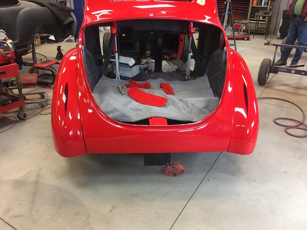A red car is being worked on in a garage