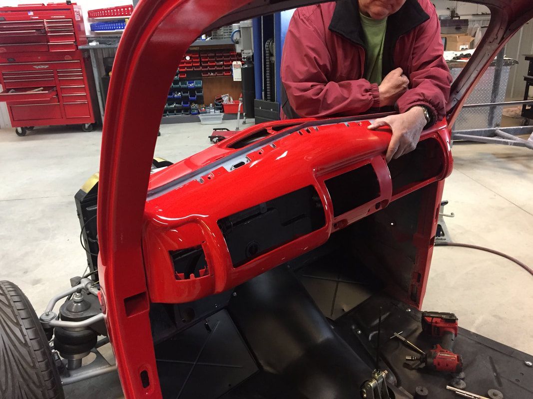A man is working on a red car in a garage