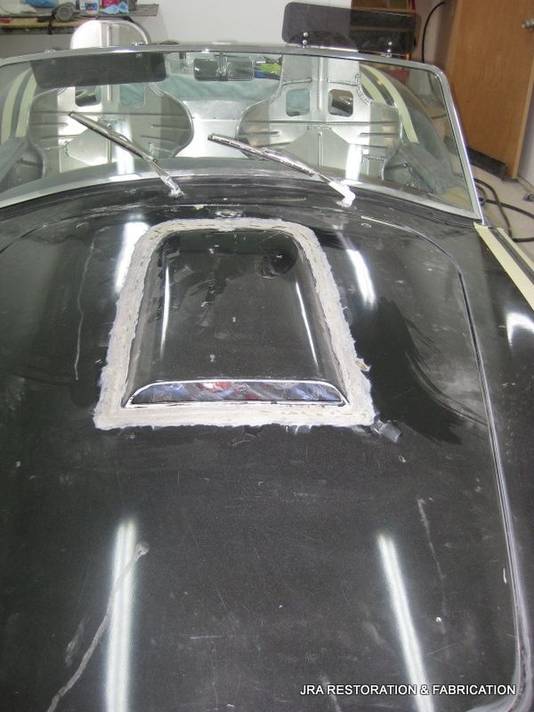 A black car with a hood that has a hole in it