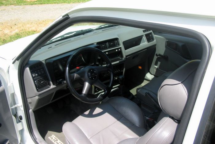 The interior of a white car with a steering wheel and seats