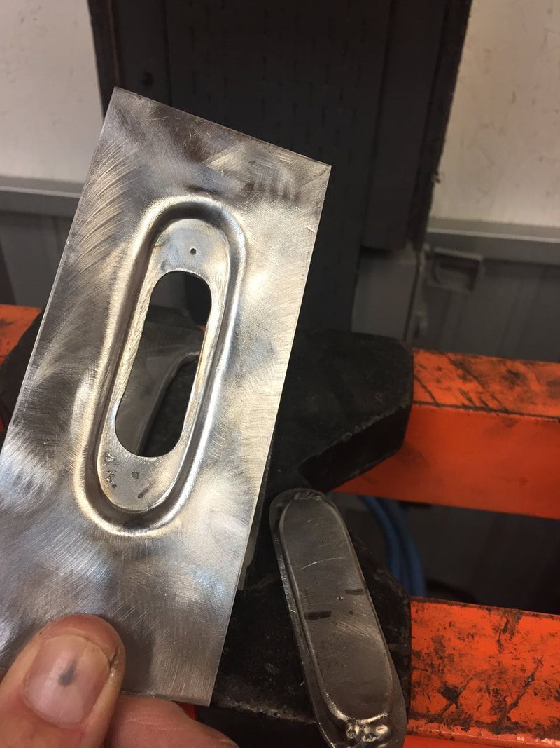 A person is holding a piece of metal with a hole in it.