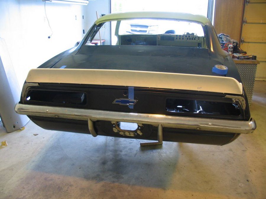 A black car with a white spoiler is sitting in a garage