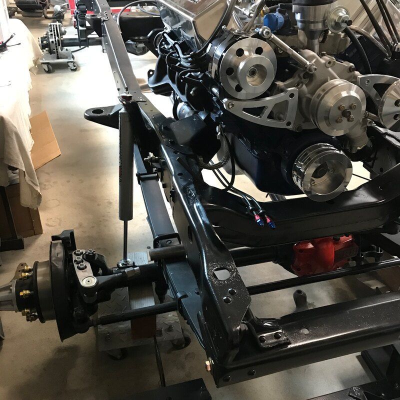 A car engine is sitting on top of a chassis in a garage.