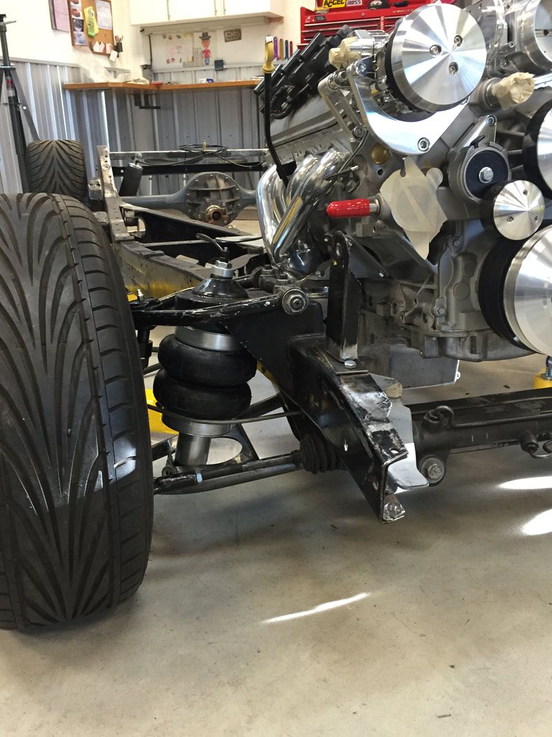 A close up of a car engine with a tire in the foreground