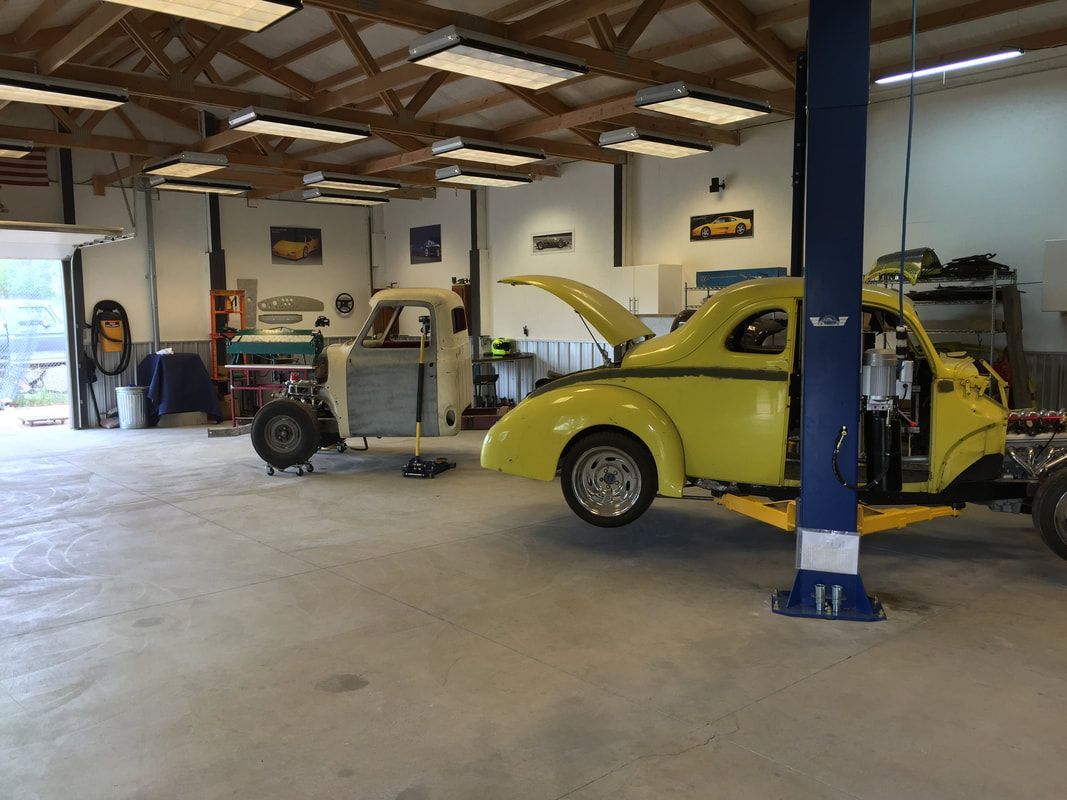 A yellow car is sitting on a lift in a garage.