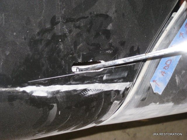 A close up of a car with a piece of blue tape on it that says jpa restoration