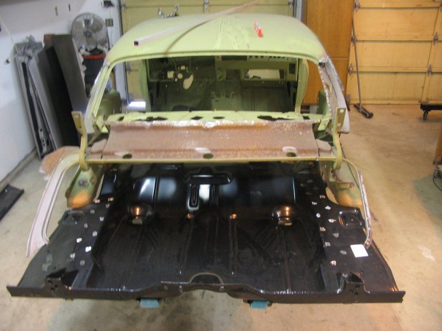 A green car is being built in a garage