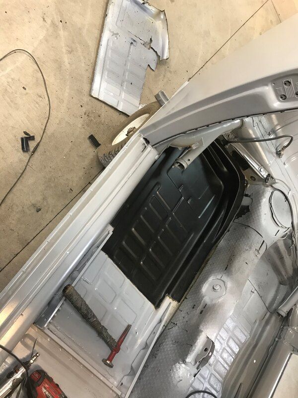 The trunk of a car is being worked on in a garage.