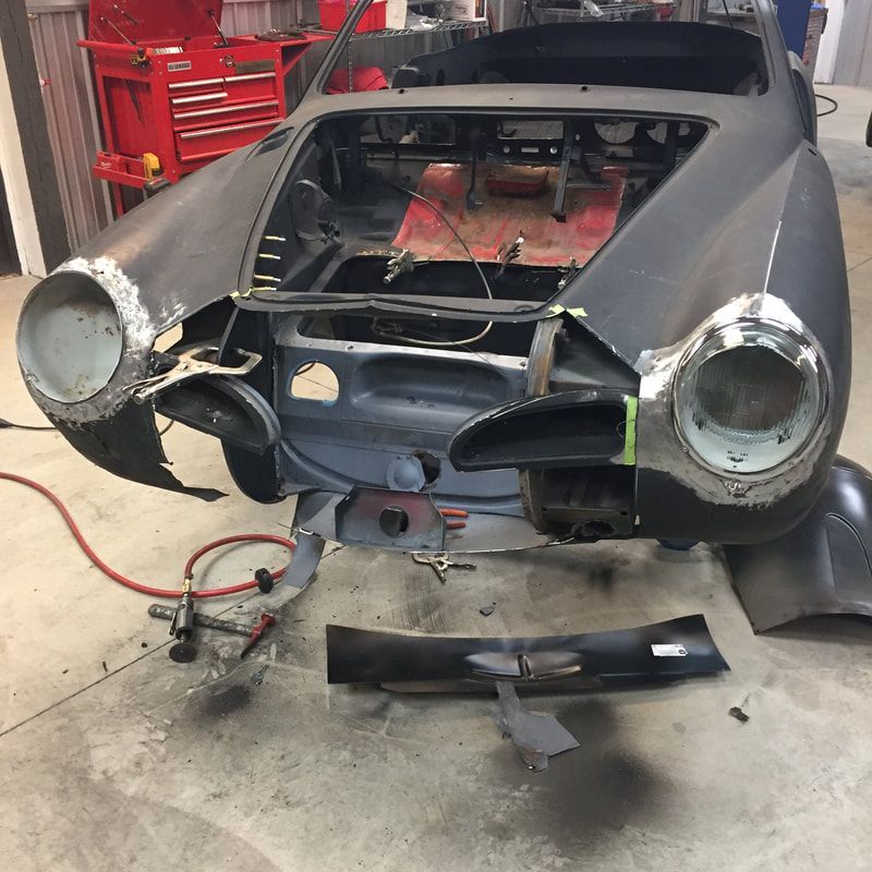 A car with the hood open is sitting in a garage