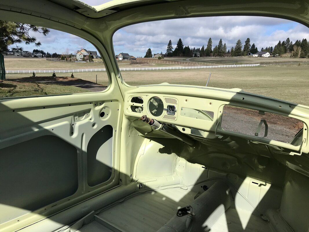 The inside of a white car with a view of a field.