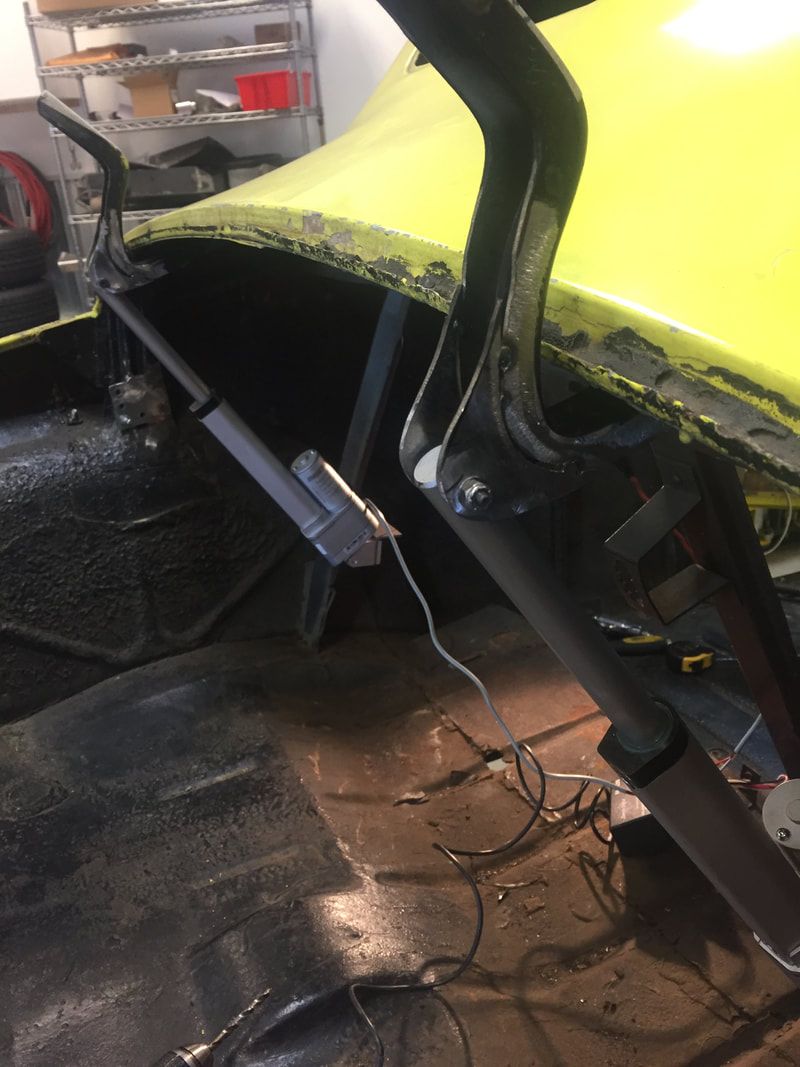A yellow car is being worked on in a garage