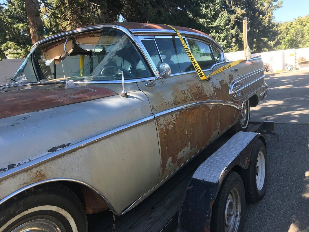 A rusty 1958 Buick Roadmaster is sitting on top of a trailer.