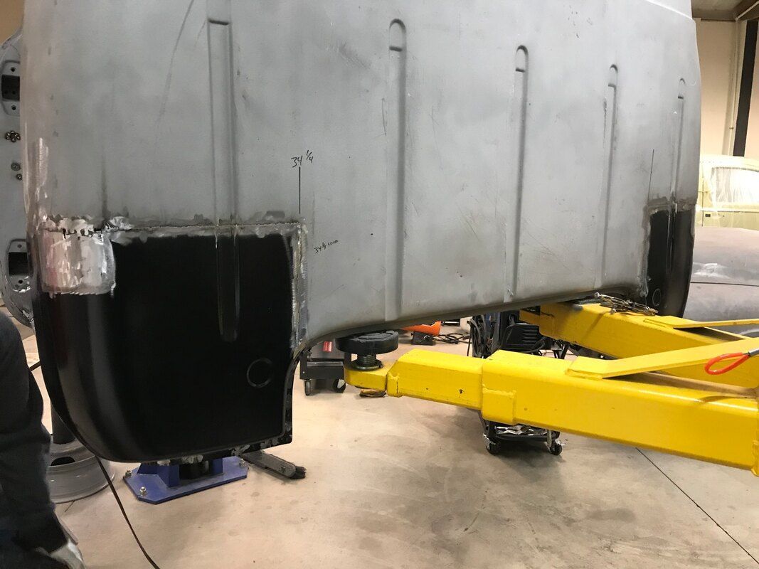 A car is sitting on a yellow lift in a garage.