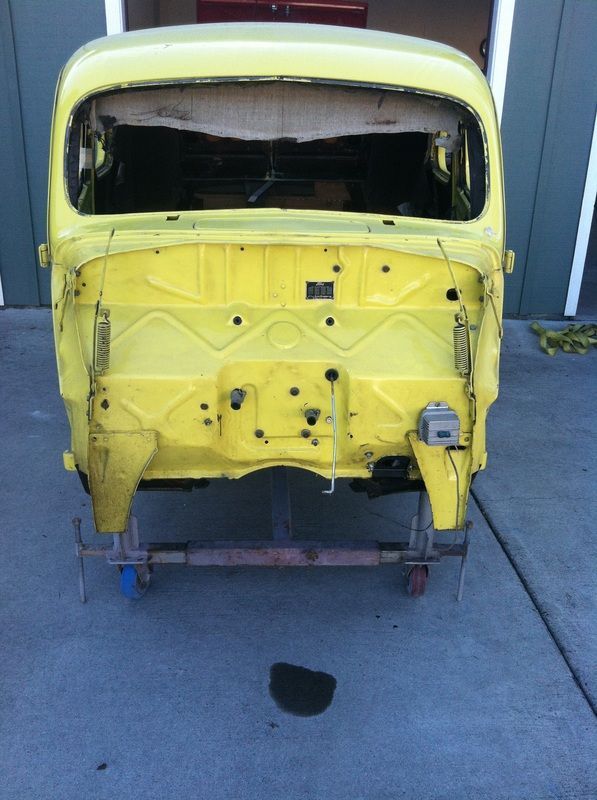 A yellow car is sitting on a cart in front of a garage door