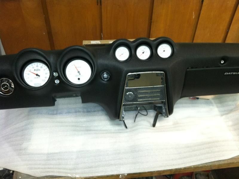 A black car dashboard with white gauges and buttons