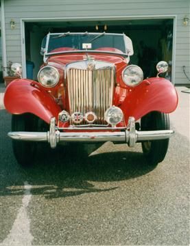 A red car is parked in front of a garage.