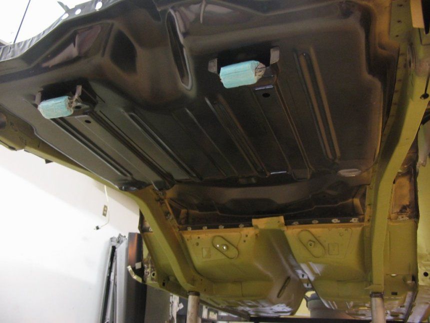 The bottom of a car is shown in a garage