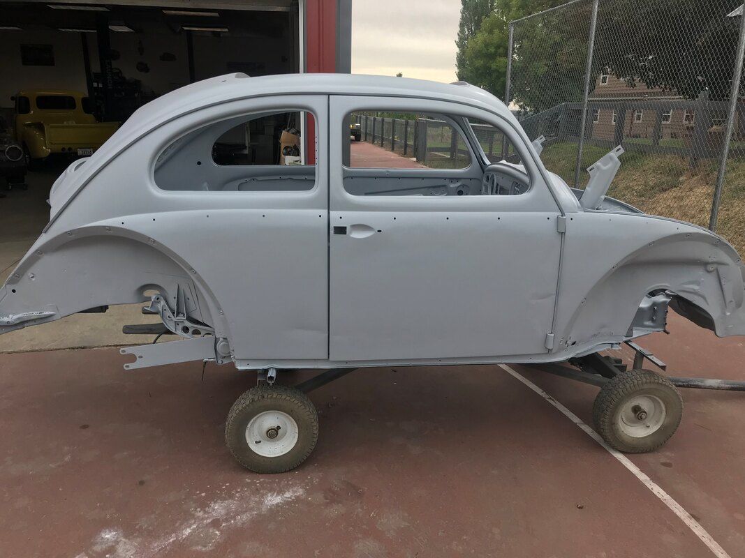 A volkswagen beetle is sitting on a trailer in a parking lot.