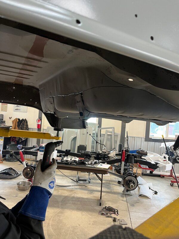 A person wearing blue gloves is working on a car