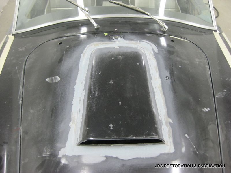 The hood of a black car is being repaired