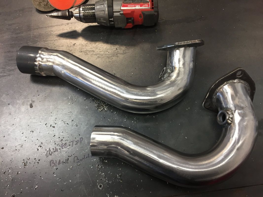 Two metal pipes are sitting on a table next to a drill.