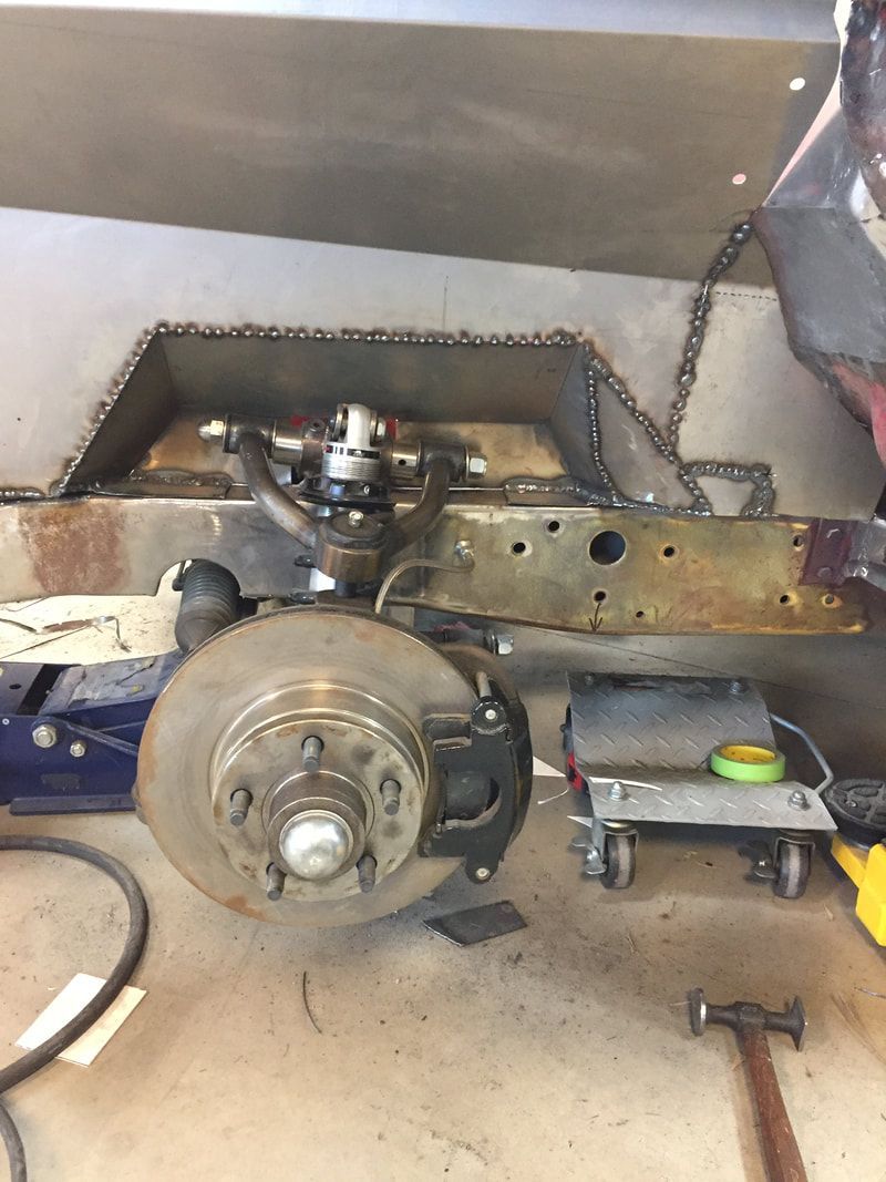 A brake disc is sitting on the ground next to a hammer.