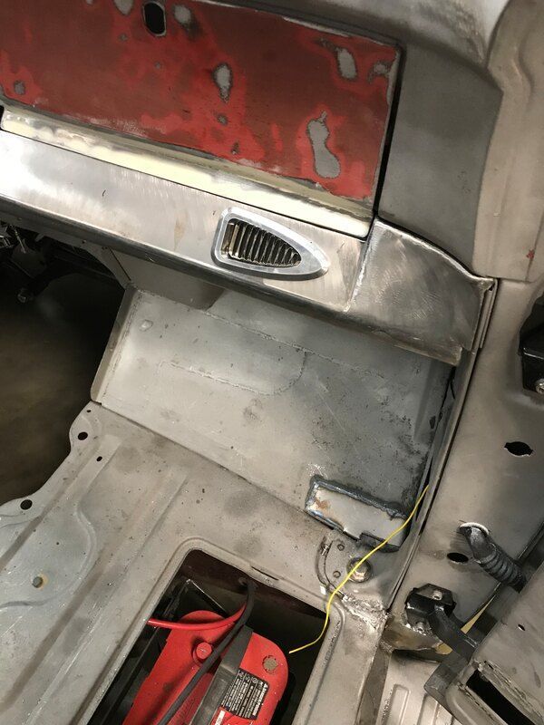 A red battery is sitting in the trunk of a car.