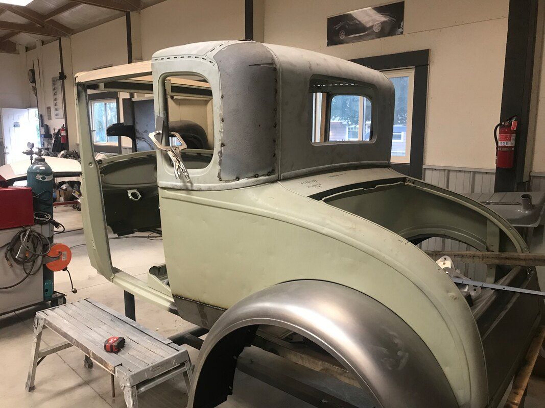 An old car is being restored in a garage.