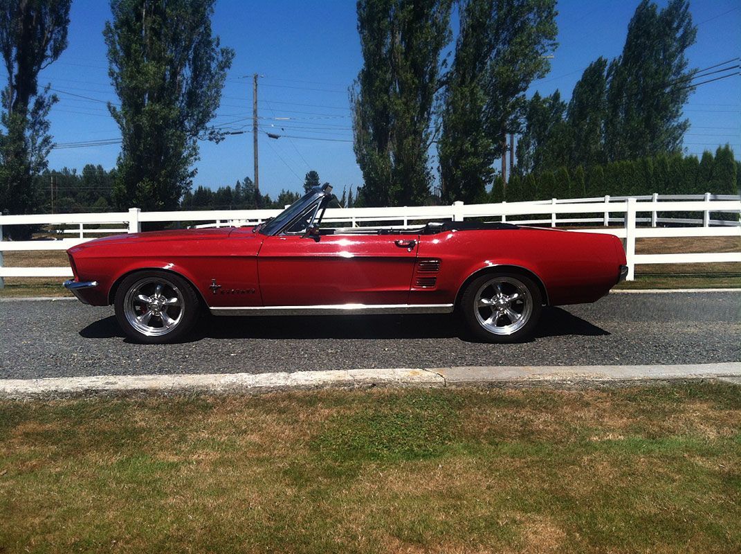 A red mustang convertible is parked on the side of the road