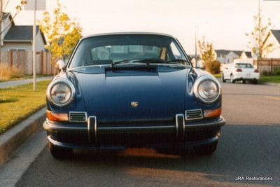 A blue porsche is parked on the side of the road