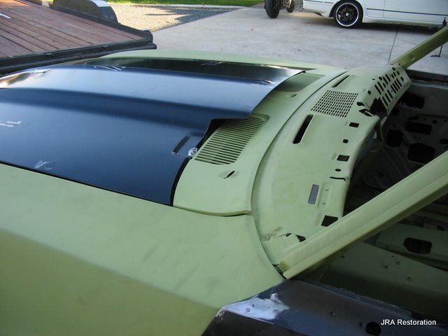 A yellow car with the hood open is parked in a driveway