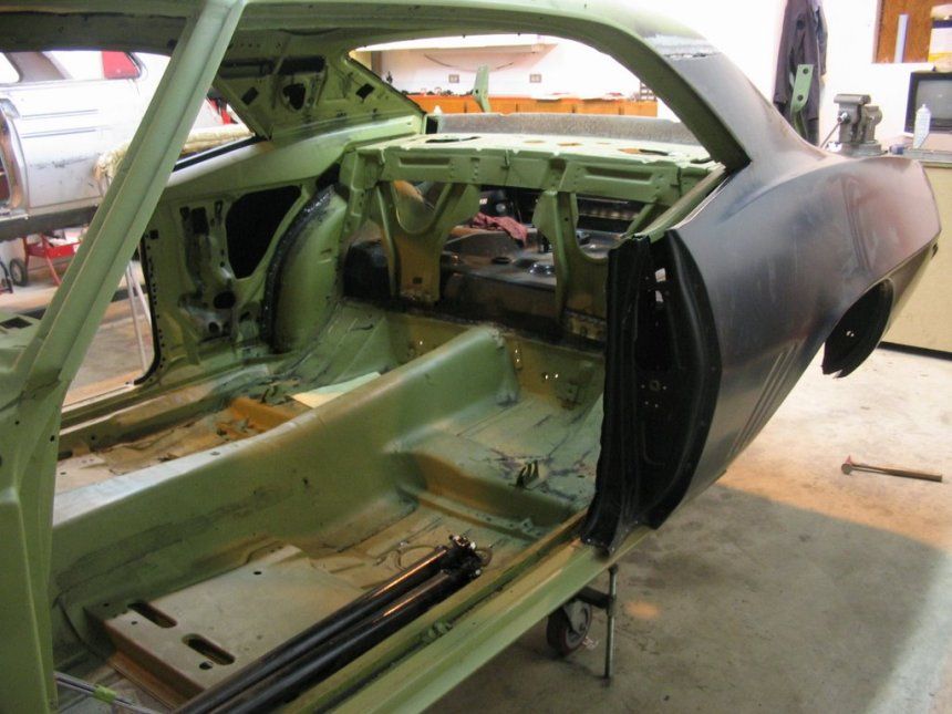 A green car is being built in a garage