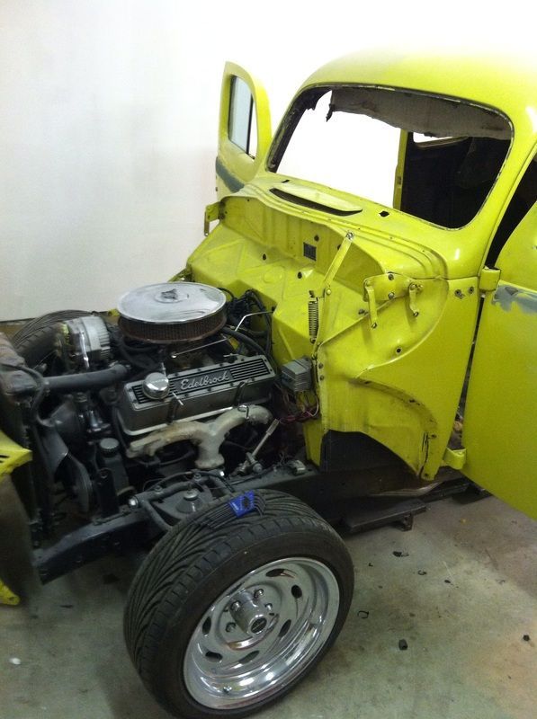 A yellow car with the hood open is sitting in a garage