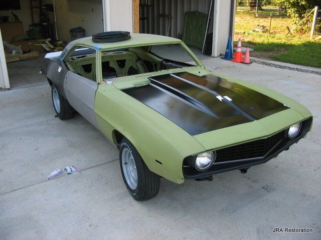 A green car is parked in front of a garage