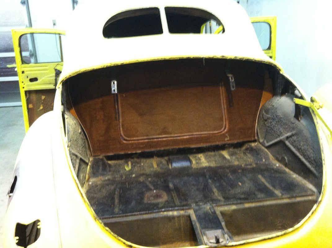 A yellow car with the trunk open and the door open