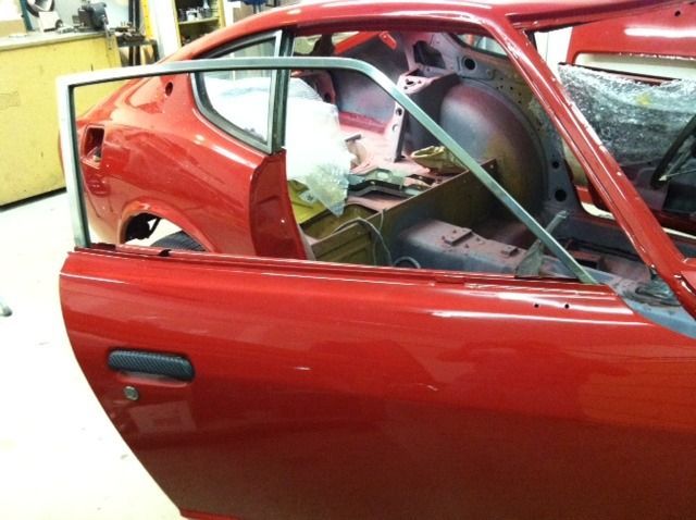 A red car with the door open in a garage