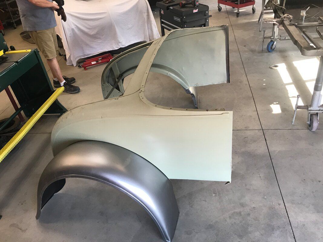 A man is standing next to a piece of metal in a garage.