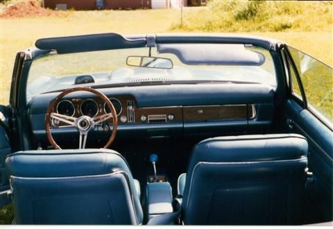 The interior of a blue convertible with a wooden steering wheel