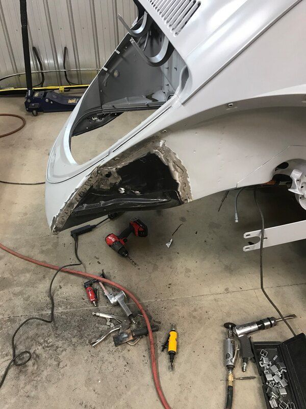 A white car is being worked on in a garage.