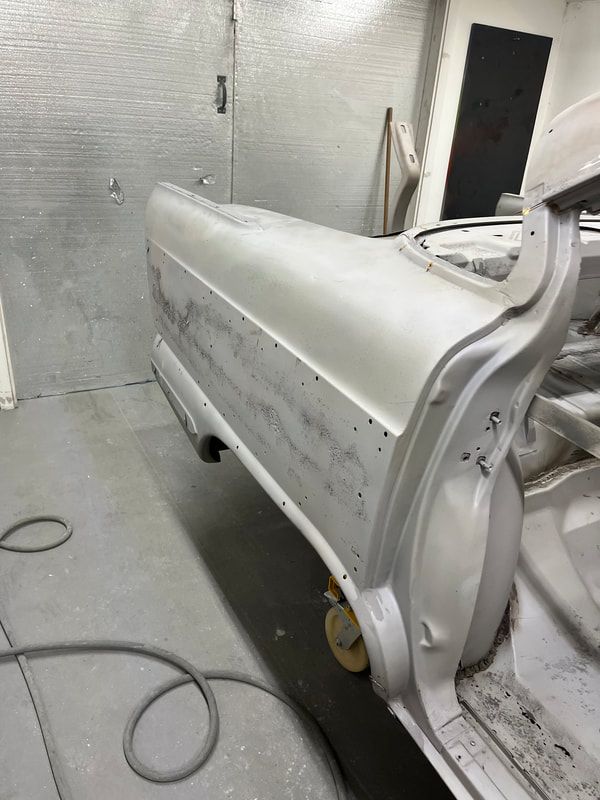 A white car is being painted in a garage.