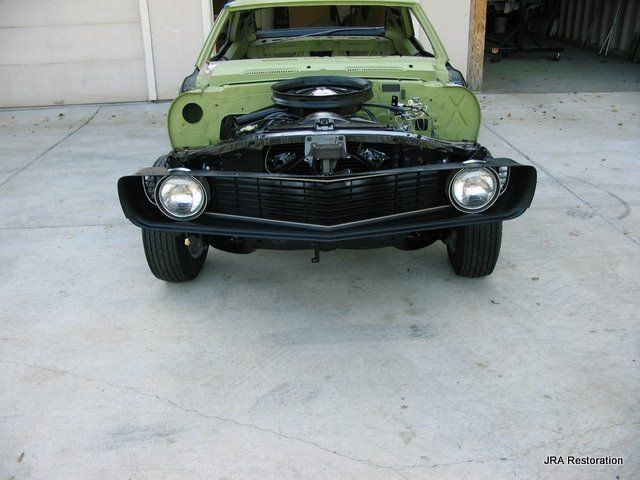 A green car with the engine removed is parked in a garage