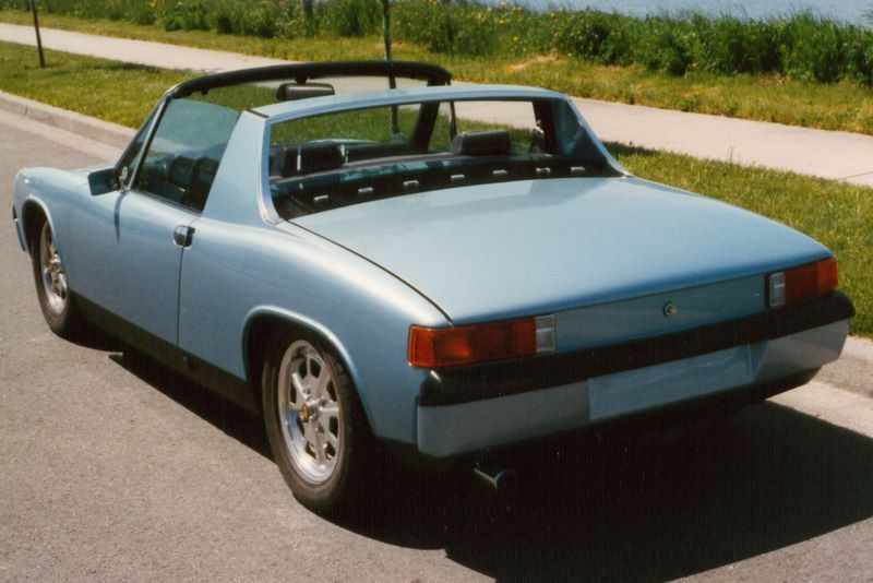 A blue car with a black top is parked on the side of the road