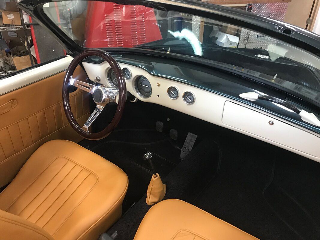 The interior of a car with brown leather seats and a wooden steering wheel.