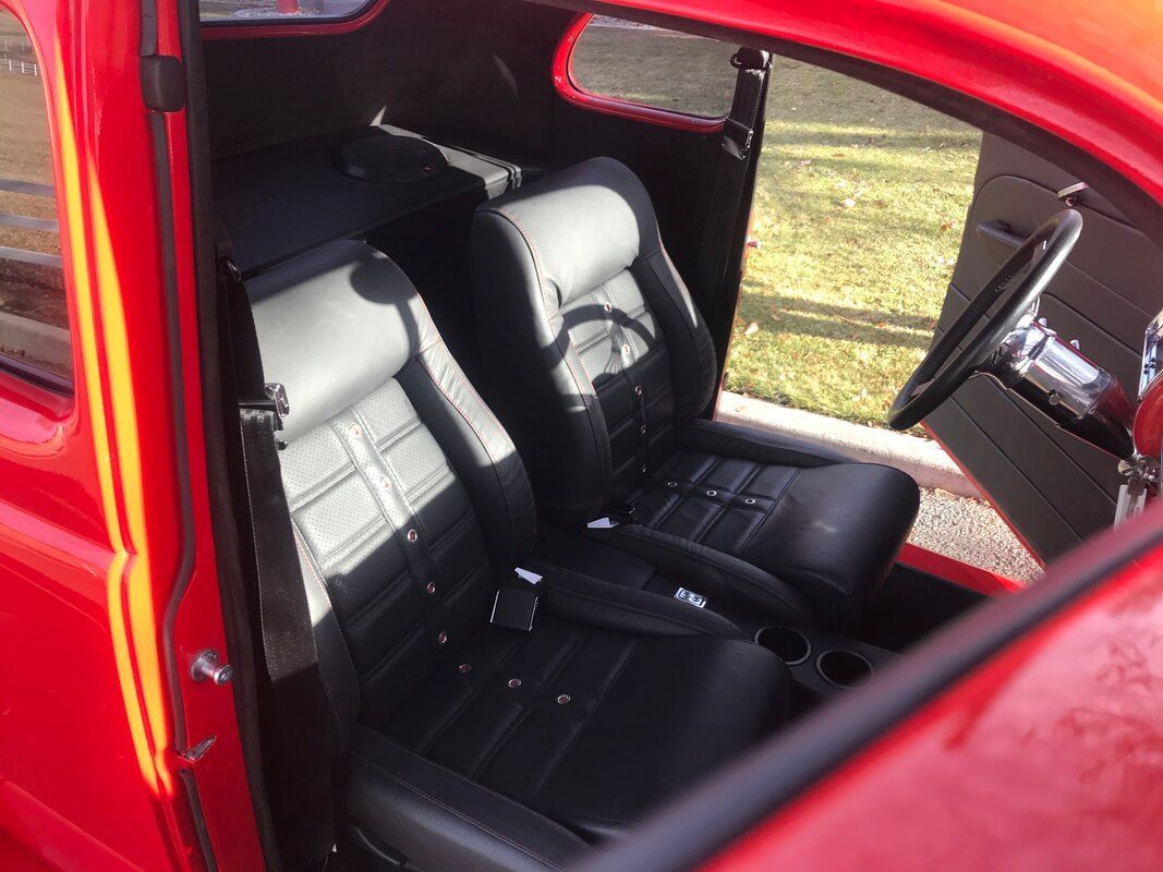 The inside of a red car with black seats and a steering wheel