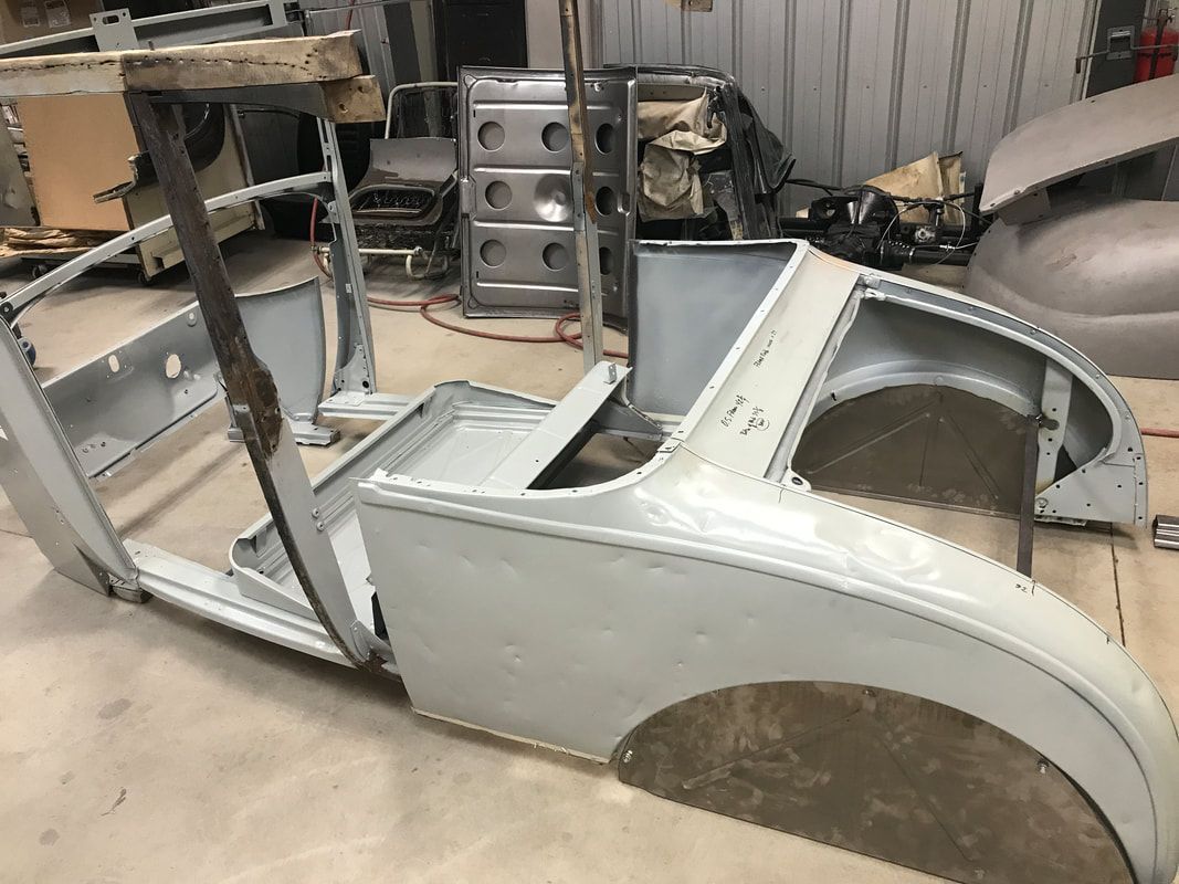 A white car body is sitting on a table in a garage.