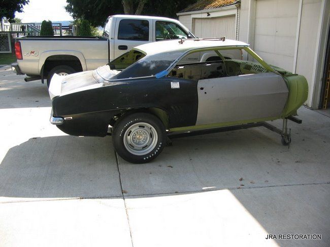 A truck is parked next to a car that is being built