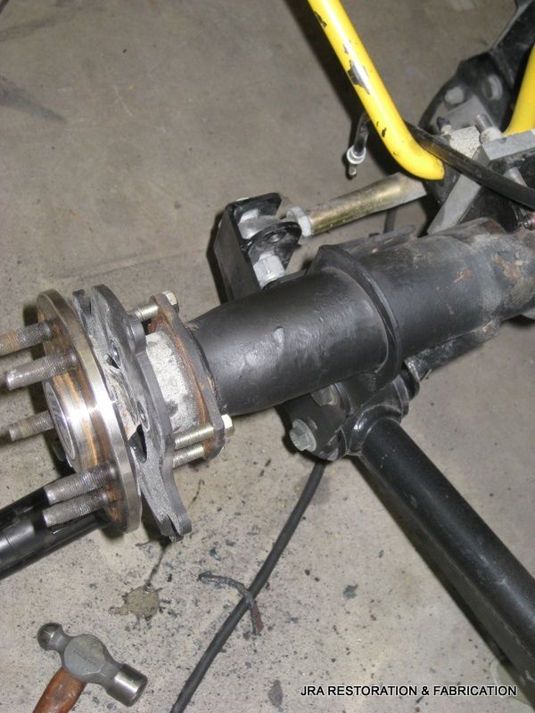 A hammer is laying on the ground next to a black pipe