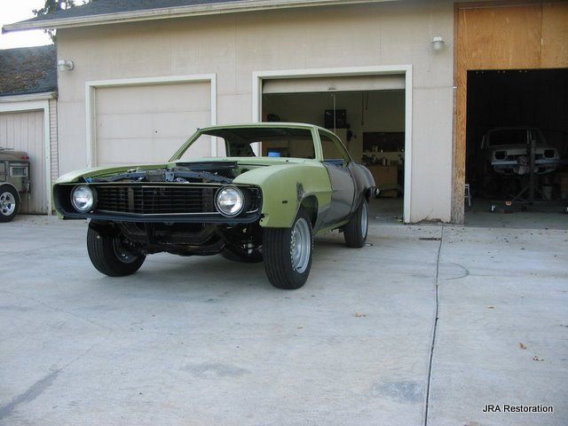 A green car is parked in front of a garage