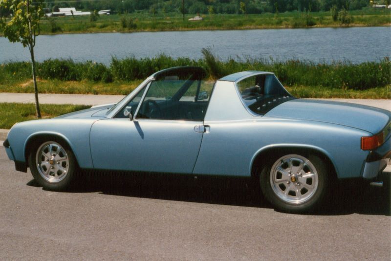 A blue car is parked in front of a body of water