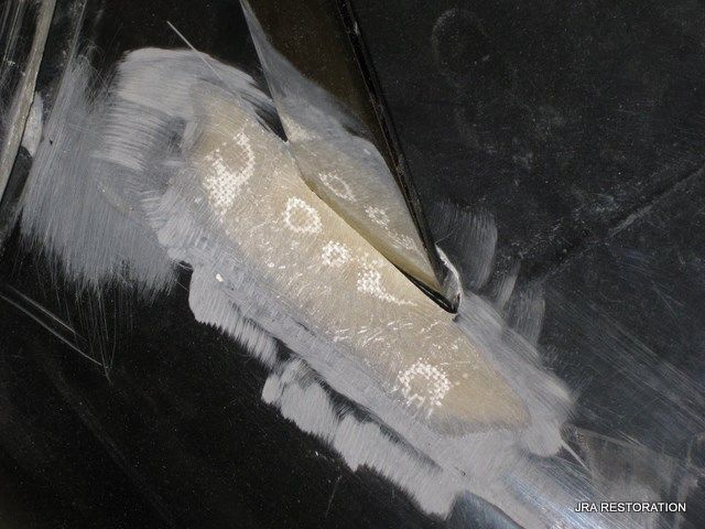 A close up of a piece of metal being repaired with a spatula.